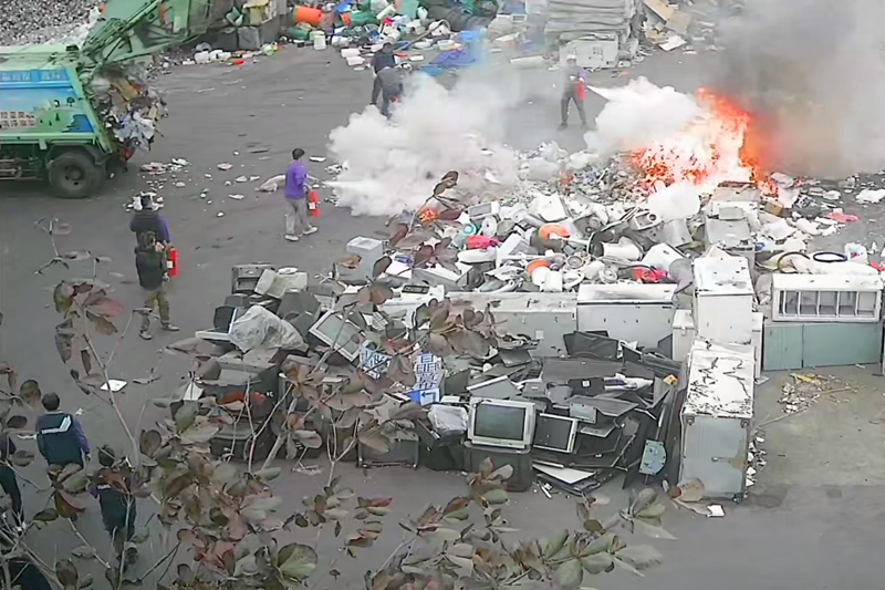 垃圾車倒出垃圾堆起火燃燒,環保人員拿乾粉滅火器進行初期滅火。